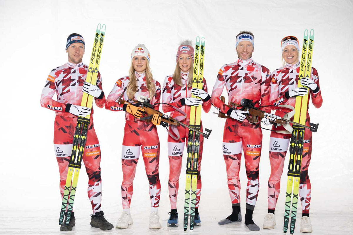 Fünf Athletinnen und Athleten des ÖSV Nordic Teams in rot-weißen Rennanzügen mit Langlaufski